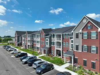 A row of apartments with a parking lot in the foreground